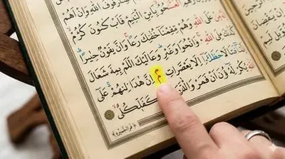 Student following Quran text with finger while learning Tajweed